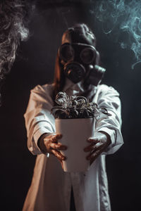 Midsection of man wearing mask against black background