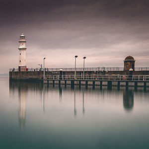 Pier over sea against sky during sunset