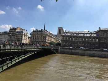 Bridge over river against sky in city