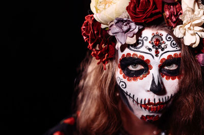 Close-up portrait of woman wearing mask against black background