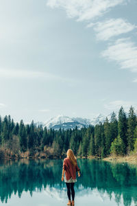 Rear view of woman standing by lake