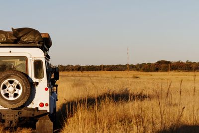 Abandoned car on field against clear sky