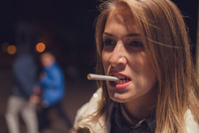 Close-up of woman biting cigarette while standing outdoors