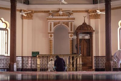 Rear view of man sitting in mosque