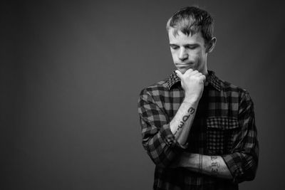 Portrait of young man standing against black background