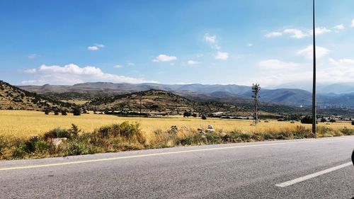 Road leading towards mountains against sky