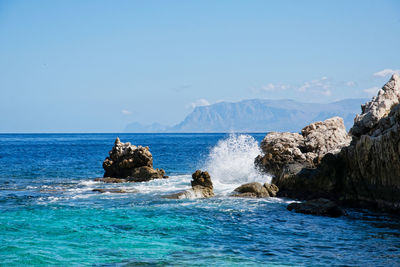 Scenic view of rocks in sea against sky