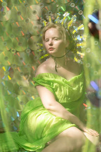 Portrait of young woman sitting against cd case 