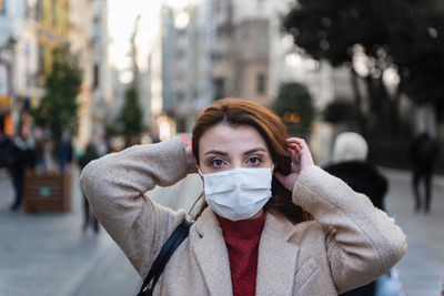 Portrait of woman wearing mask standing on city street