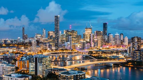 Illuminated buildings in city against cloudy sky