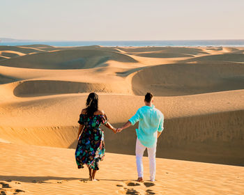 Rear view of people walking at desert