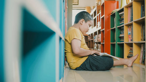 Side view of young man reading book