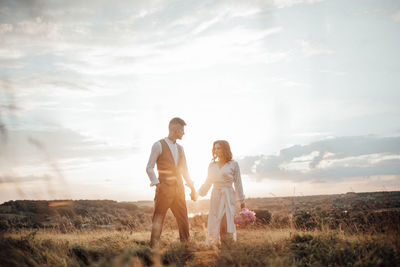 Couple standing on field against sky