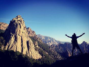 Silhouette of person on mountain against clear sky