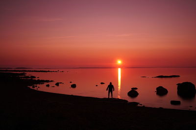 Silhouette people on beach against sky during sunset