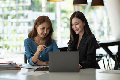 Smiling businesswoman with colleague working at desk in office