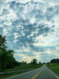 Road by trees against sky