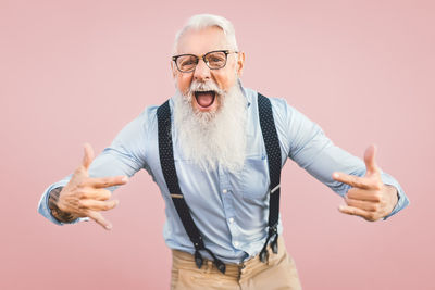 Portrait of mature man standing against gray background