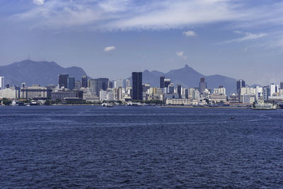 Sea by city buildings against sky