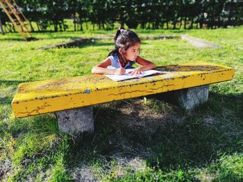 Girl writing in book at bench