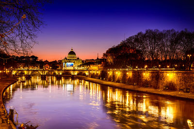River and illuminated st peter basilica against sky at dusk