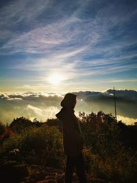 Silhouette man standing on mountain against sky during sunset