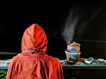 Rear view of person standing by food in table 