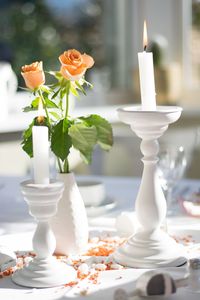 Lit candles and flower vase on table