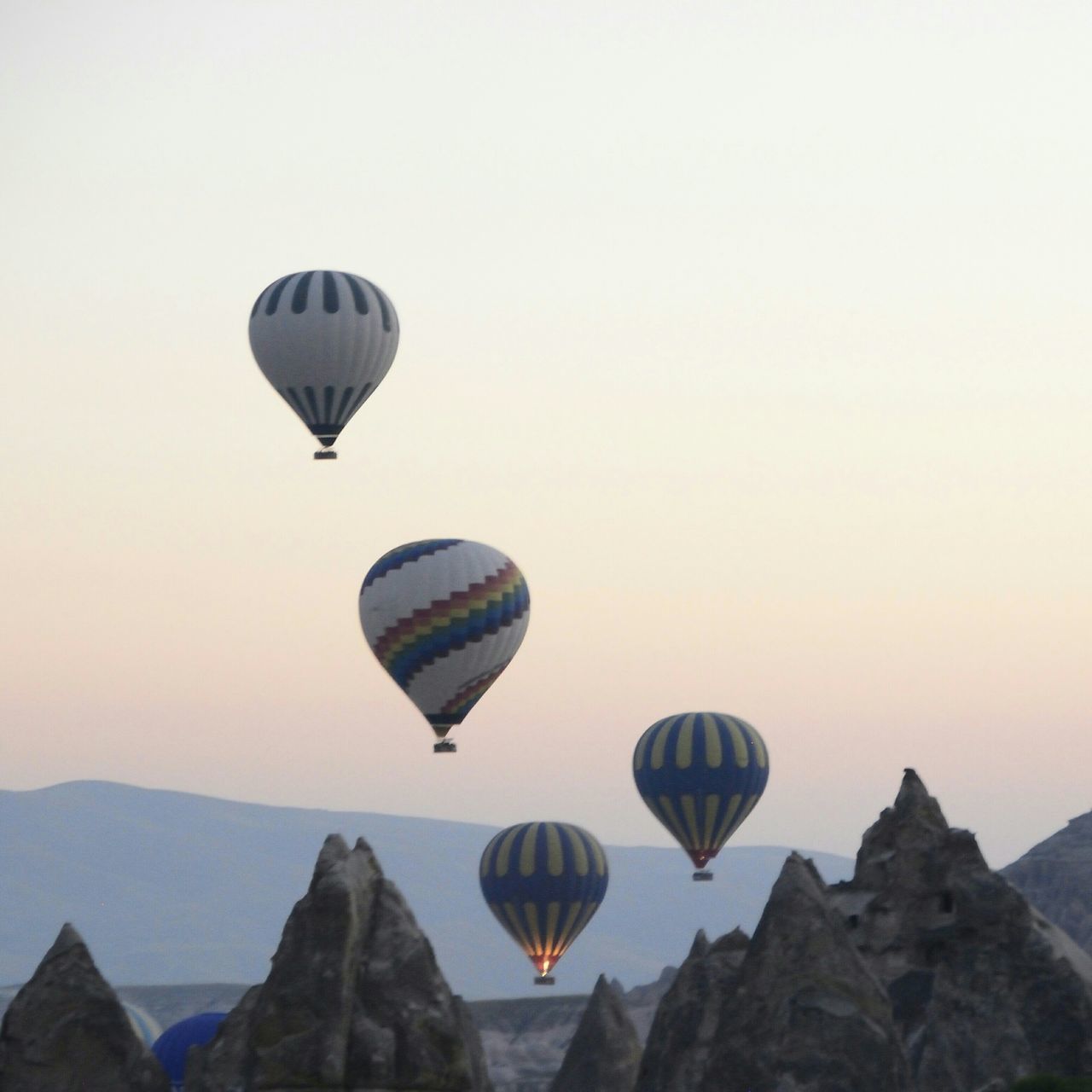 flying, mid-air, hot air balloon, parachute, adventure, clear sky, mountain, copy space, transportation, paragliding, tranquility, scenics, tranquil scene, low angle view, sky, extreme sports, leisure activity, beauty in nature, travel, nature