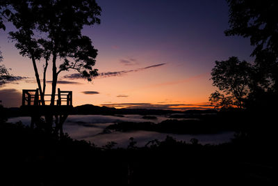 Silhouette trees on landscape against romantic sky at sunset