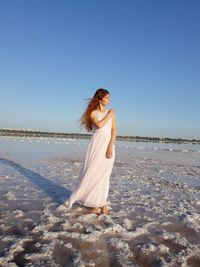 Woman on beach against clear blue sky