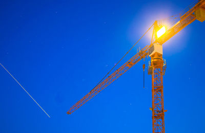 Low angle view of crane against blue sky