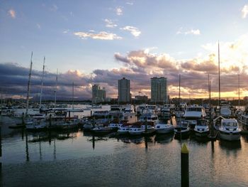 Boats moored in harbor at sunset