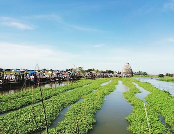 Panoramic view of people by river against sky