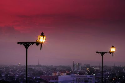 Illuminated street light against sky at night