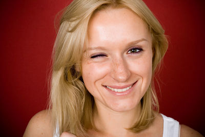 Portrait of pretty blonde woman on red background