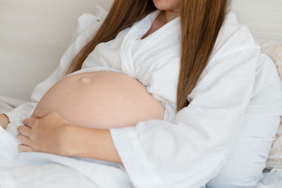 Midsection of pregnant woman lying on bed