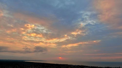 Scenic view of sea against dramatic sky during sunset
