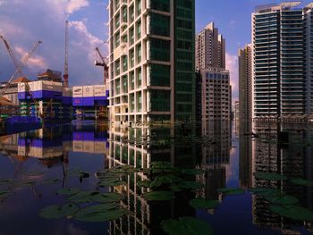Reflection of cityscape in lake against sky