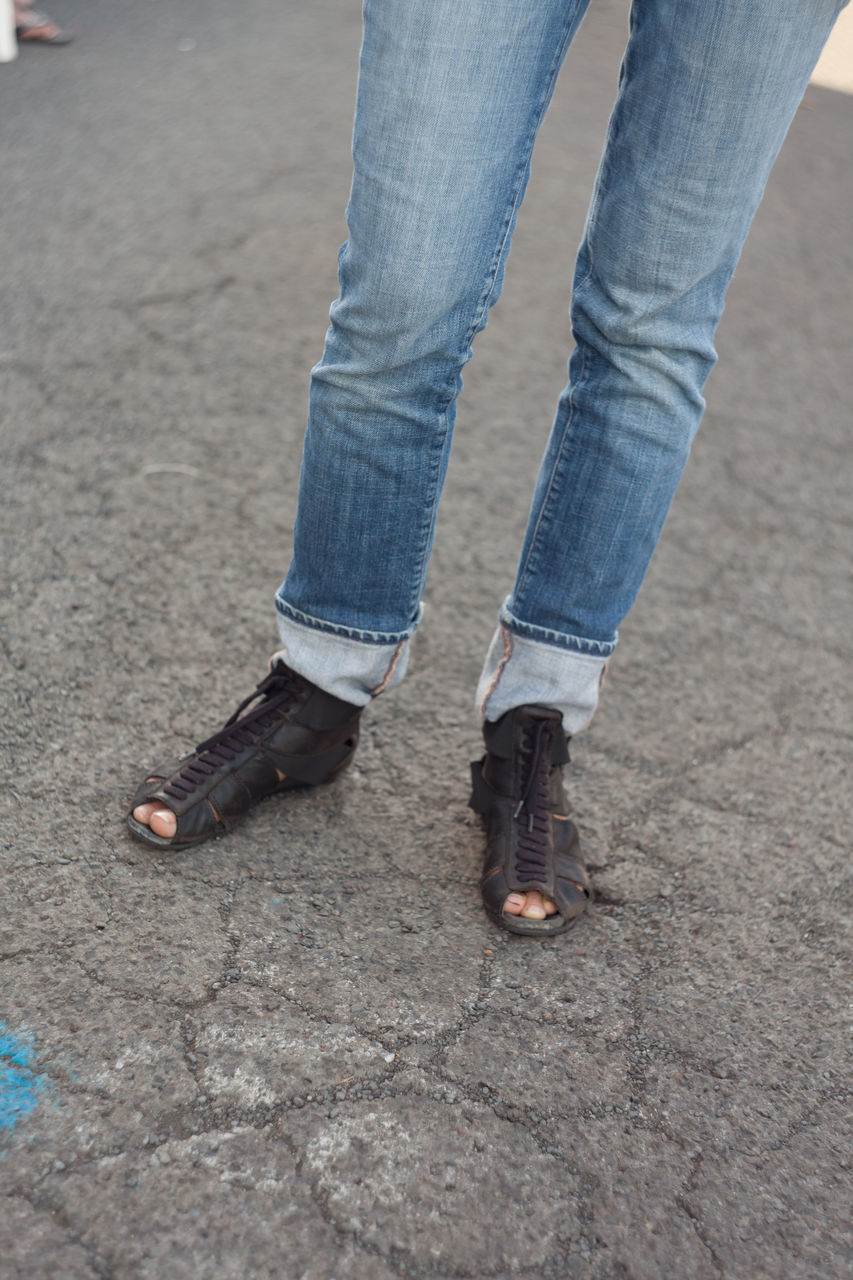 LOW SECTION OF WOMAN STANDING ON ASPHALT