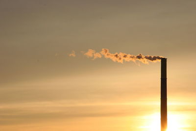 Low angle view of smoke emitting from chimney against sky during sunset