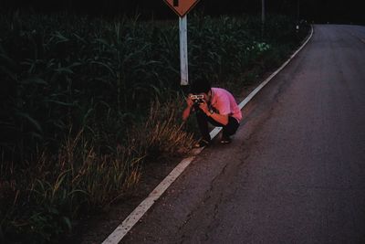 Man photographing while crouching on road