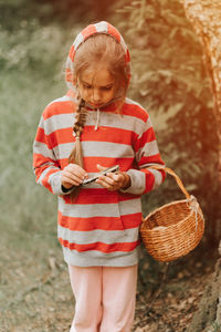 Upset or focused eight year old kid girl mushroom picker is seek for and picking mushrooms