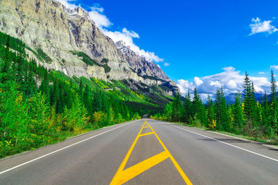 Road by mountains against sky