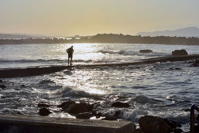 Silhouette man standing on beach against sky during sunset