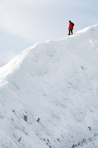 Low angle view of mountaineer climbing snowcapped mountain against sky