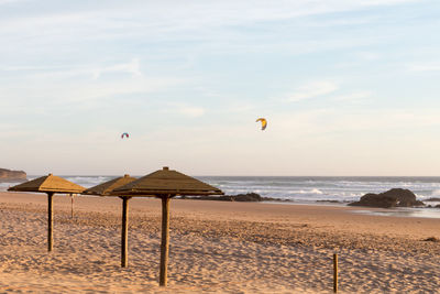 Parasols at beach against sky during sunset