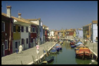 Boats moored in canal amidst buildings against clear sky