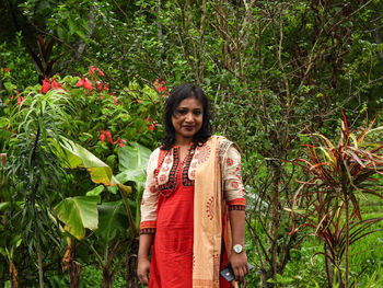 Portrait of smiling young woman standing against plants