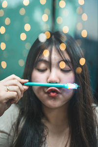 Beautiful woman making face while holding pen against illuminated light